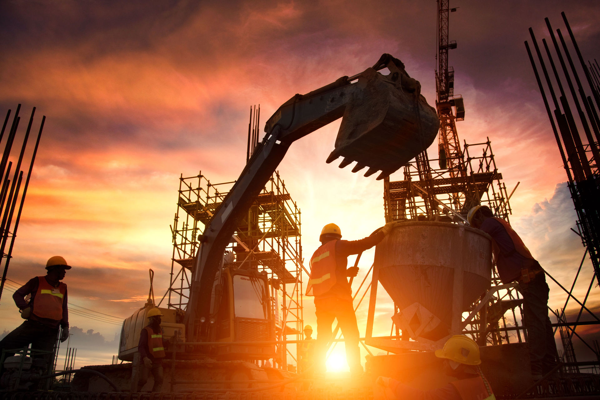 Construction site at sunset, workers and crane on a reinforced concrete structure